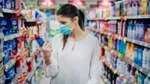 Woman wearing protective mask in a supermarket shopping for cleaning products.