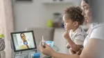 Woman with child on lap, discussing medicine with doctor via online appointment on her computer